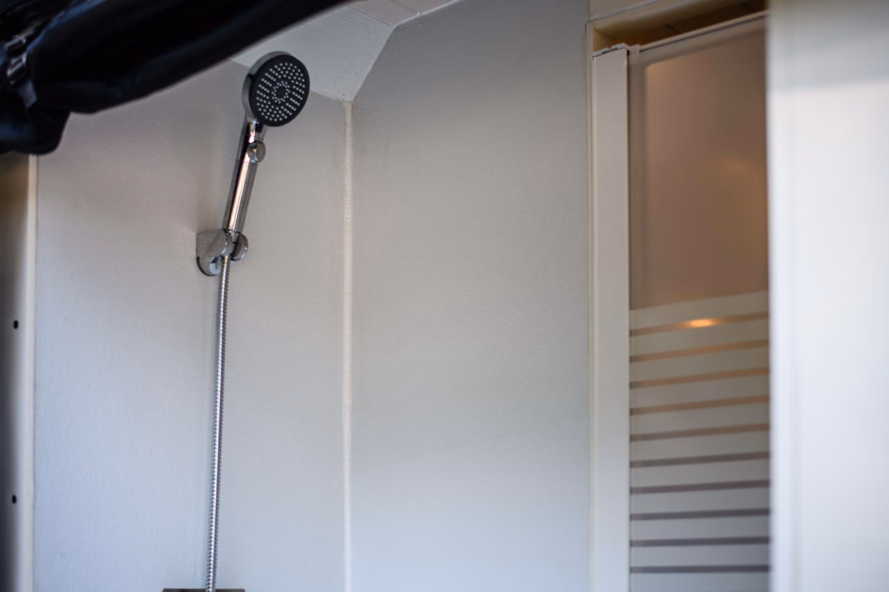 Handheld shower head mounted inside the custom camper van shower.