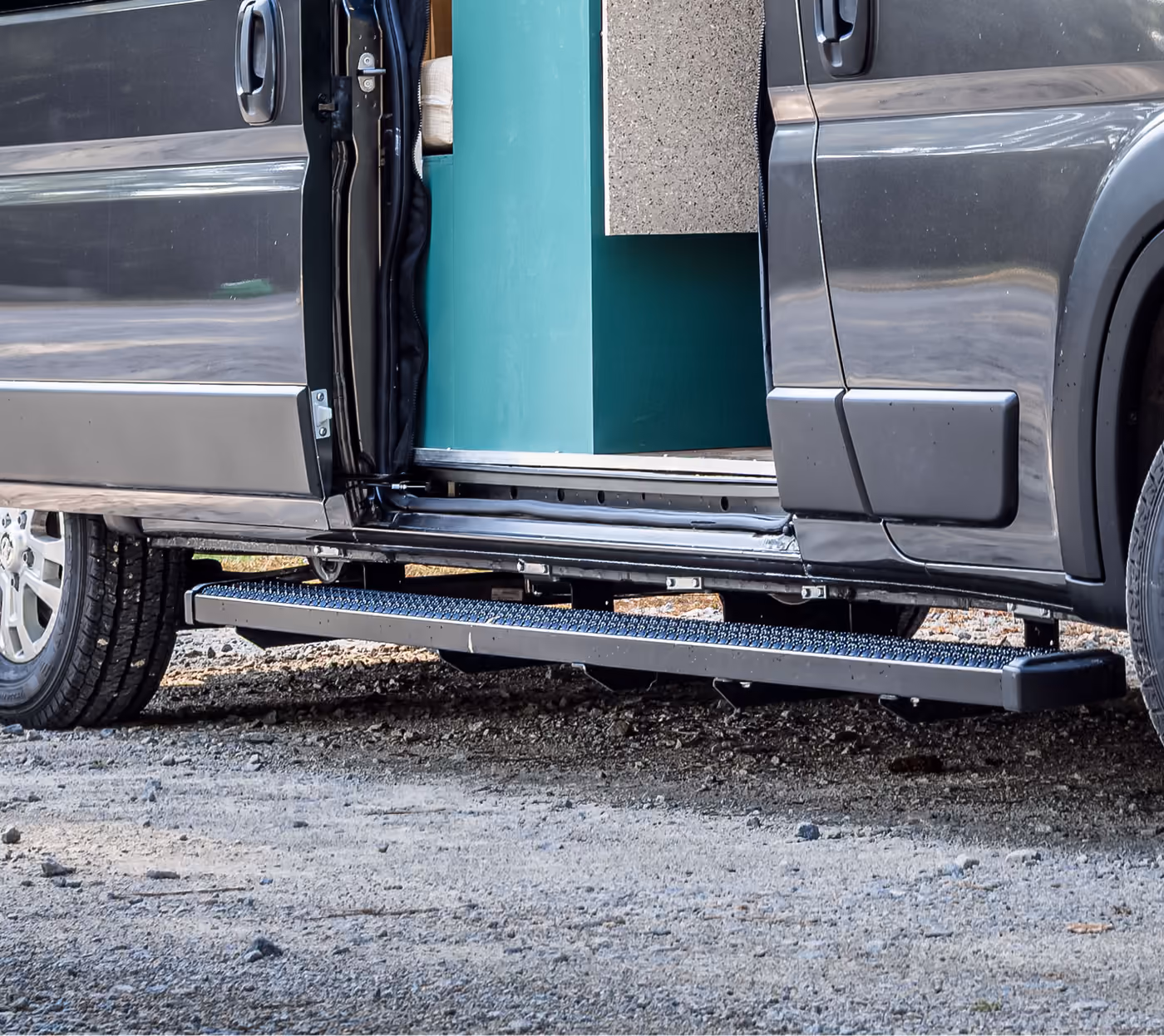 Close-up of a side running board below the sliding door of a custom camper van for easier entry.
