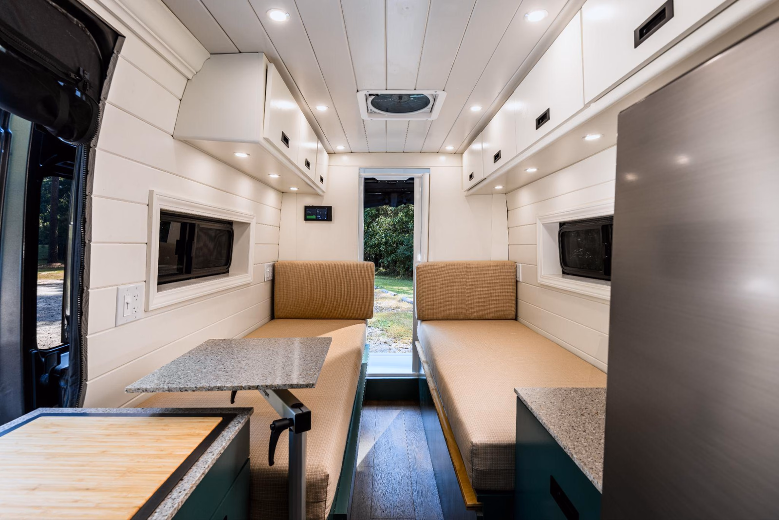 Two cushioned benches with an open aisle inside a custom camper van.