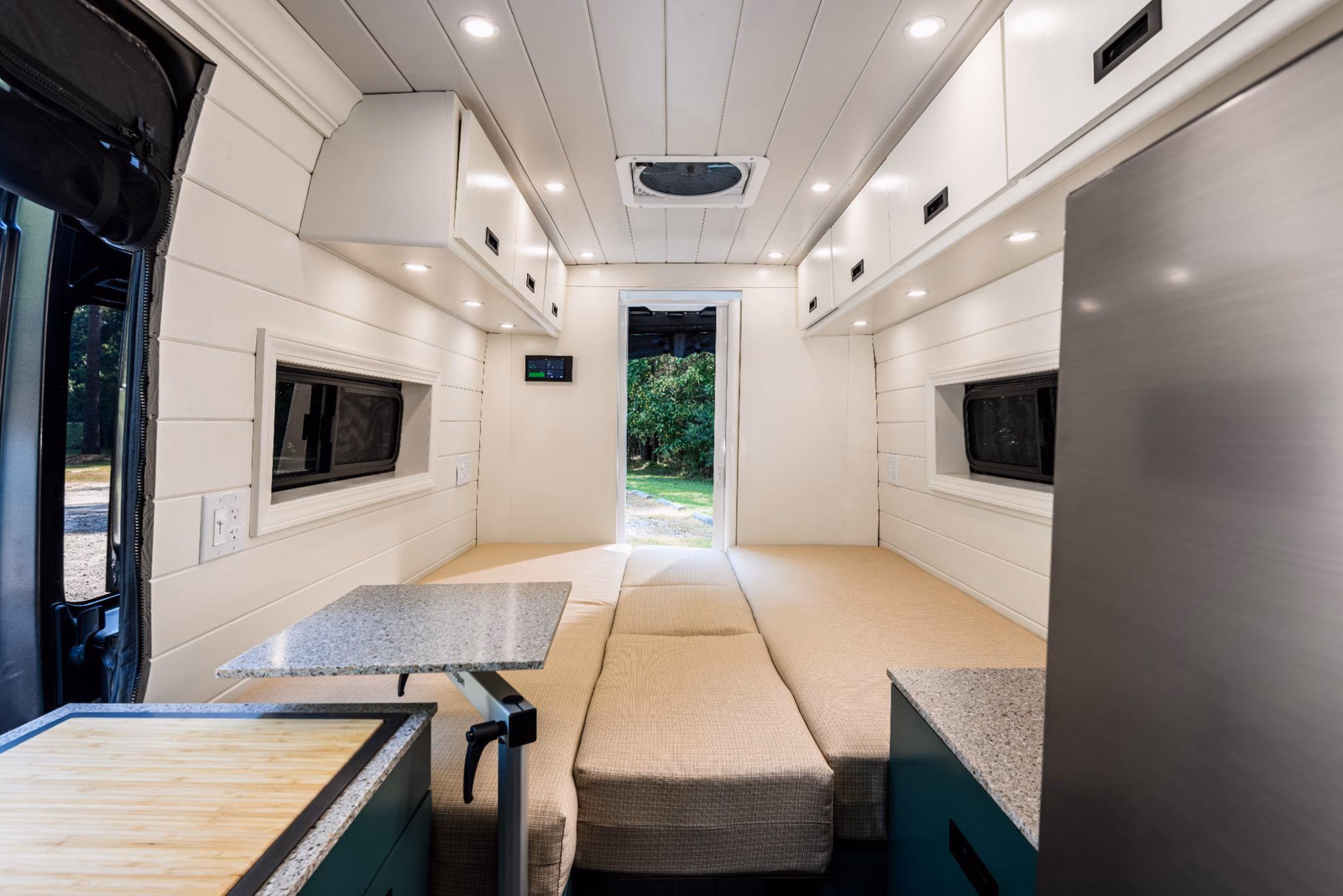 Camper van benches joined by center cushions to form a wide sleeping area.