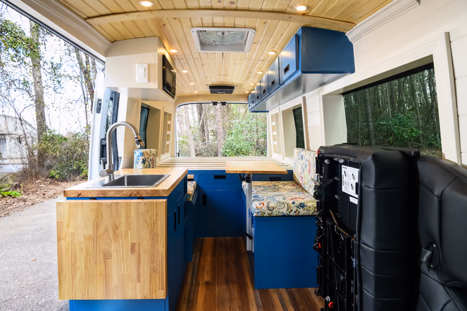 Custom campervan interior with solid wood counters and blue cabinetry